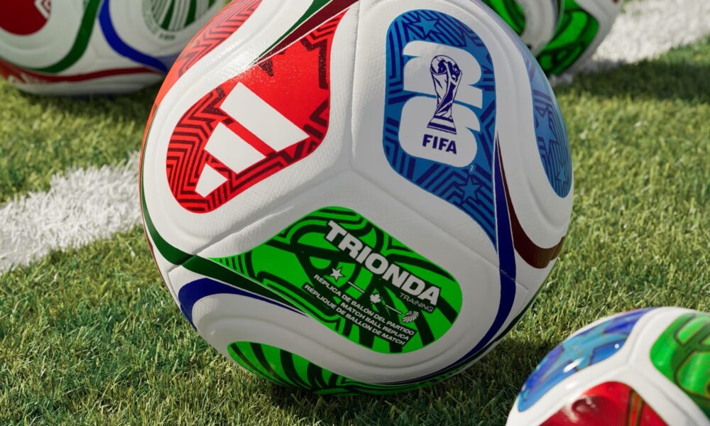 Montagem com várias bolas Adidas Trionda, bola oficial da Copa do Mundo 2026, em um gramado de estádio de futebol.