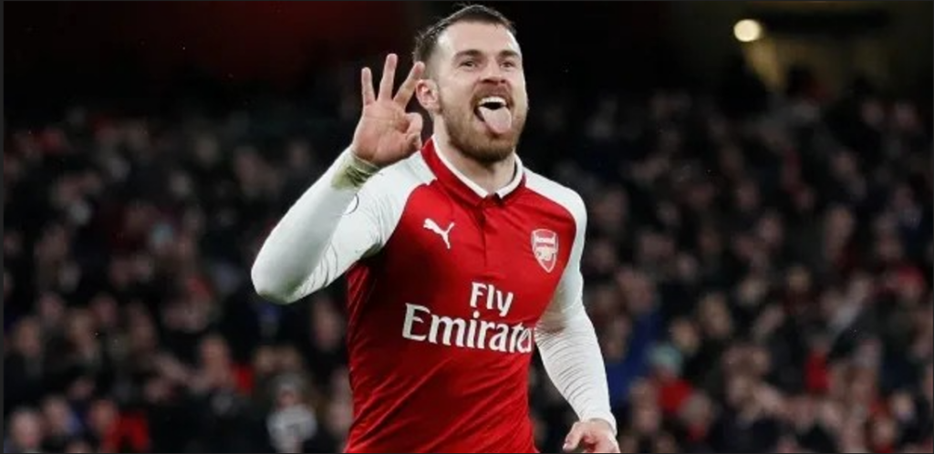 Aaron Ramsey, jogador de futebol galês, usando a camisa do Arsenal e comemorando um gol pelo clube de Londres onde jogou a maior parte da carreira.