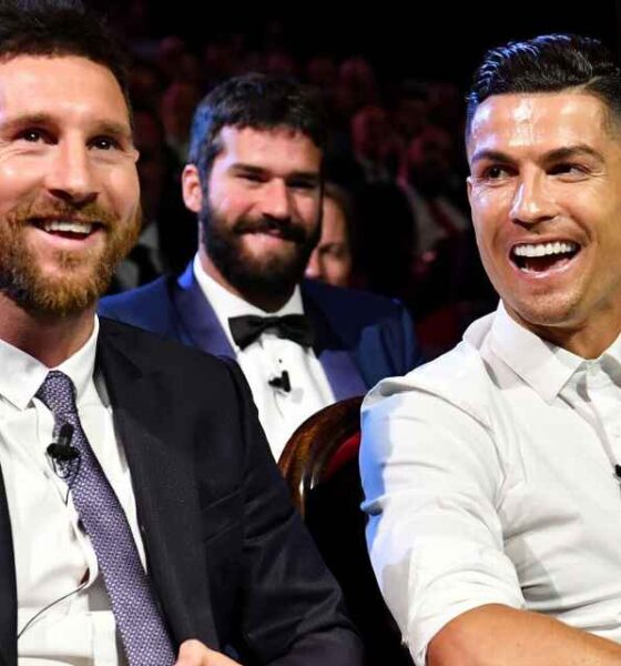 Messi e Cristiano Ronaldo sentados lado a lado e sorrindo durante sorteio dos grupos da Champions League temporada 2019/2020